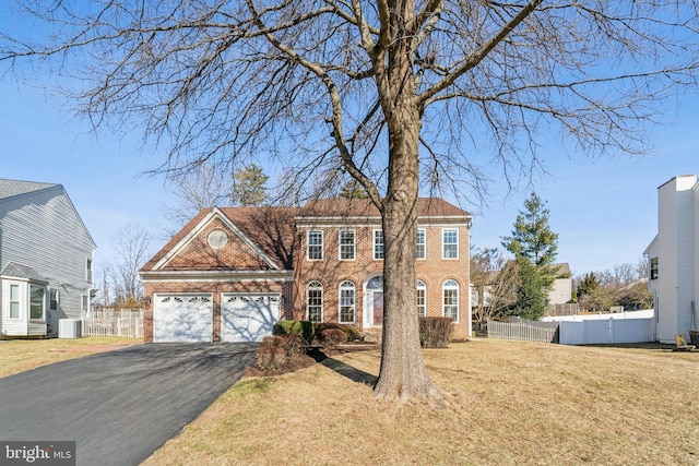 colonial-style house featuring aphalt driveway, brick siding, fence, and central AC