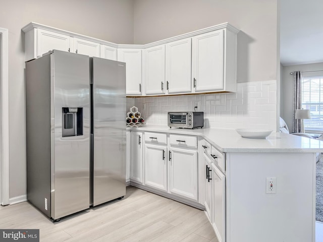 kitchen featuring a toaster, stainless steel fridge, backsplash, and white cabinetry