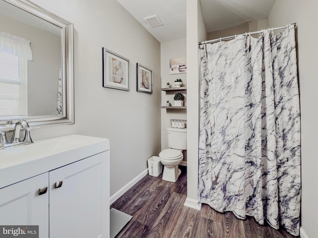 bathroom with baseboards, visible vents, toilet, wood finished floors, and vanity