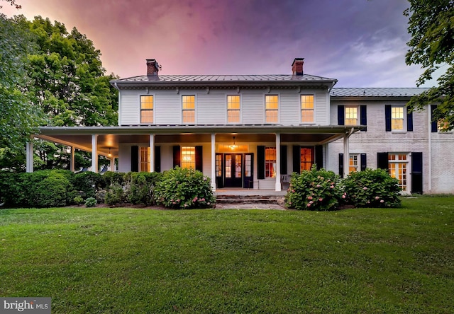 13401 Longnecker Rd, Reisterstown, MD 21136 - back of property at dusk with a standing seam roof, a chimney, covered porch, and a lawn