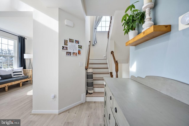 stairs featuring baseboards, a healthy amount of sunlight, and wood finished floors