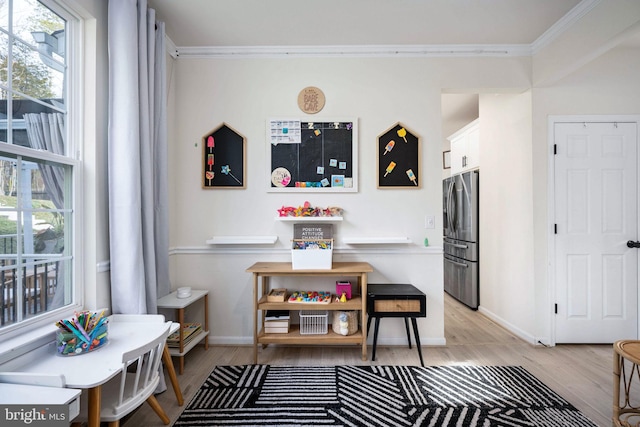 dining space with baseboards, crown molding, and light wood finished floors