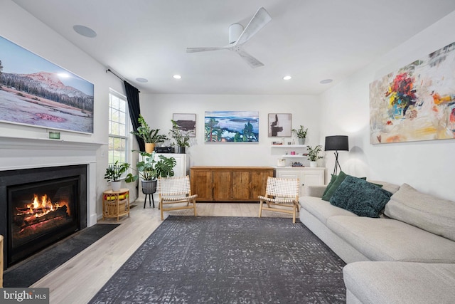 living area featuring recessed lighting, a fireplace with flush hearth, wood finished floors, and a ceiling fan