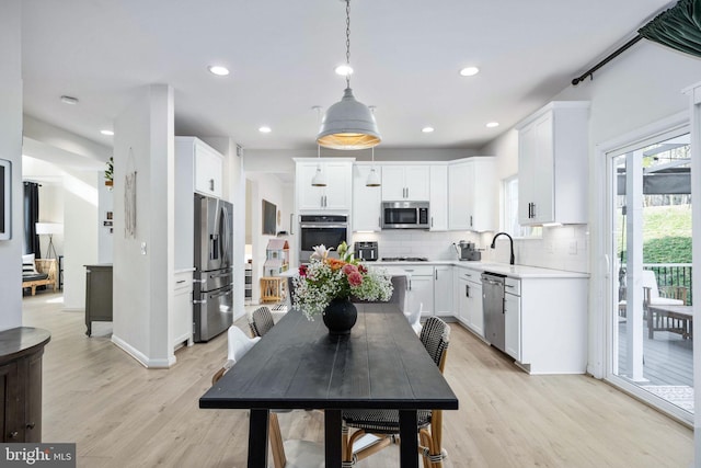 kitchen with light wood finished floors, decorative backsplash, a healthy amount of sunlight, and appliances with stainless steel finishes