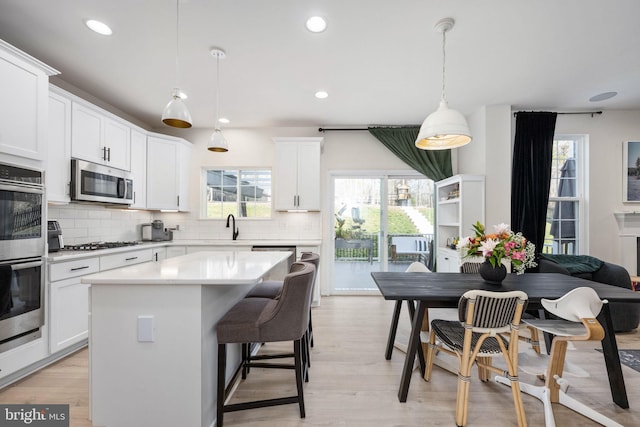 kitchen with tasteful backsplash, a kitchen island, light countertops, appliances with stainless steel finishes, and white cabinetry