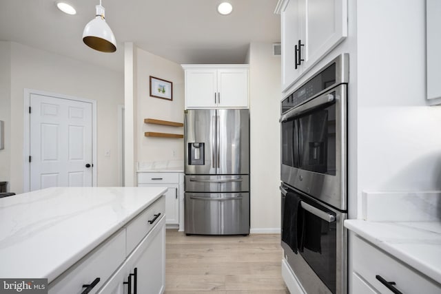 kitchen with light stone counters, white cabinets, appliances with stainless steel finishes, and light wood-type flooring