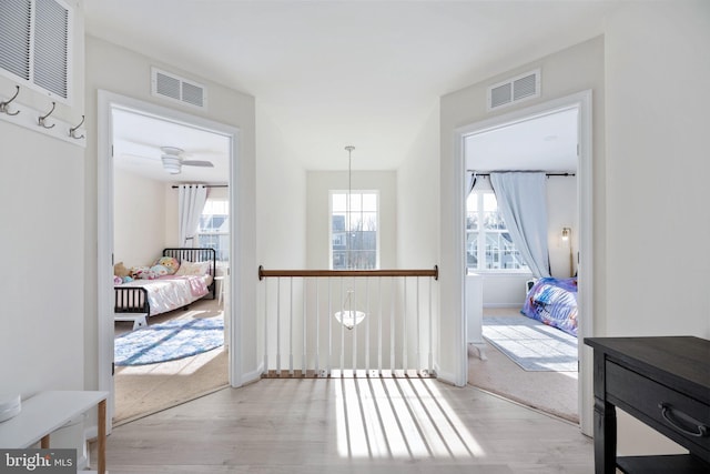 hall featuring visible vents, light wood-type flooring, and baseboards