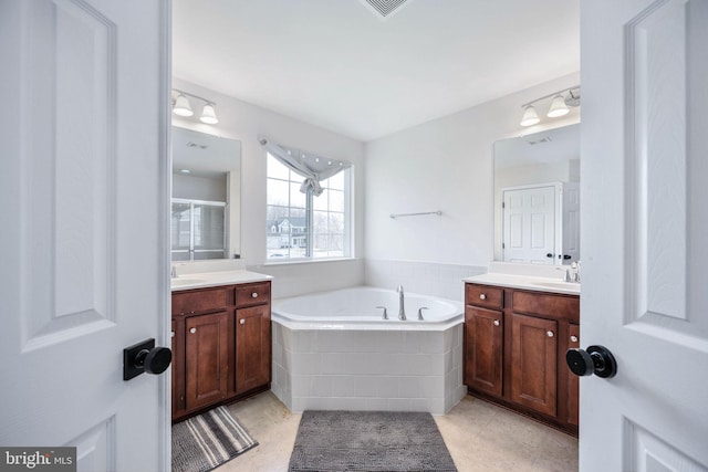 full bathroom with a sink, two vanities, a bath, and tile patterned floors