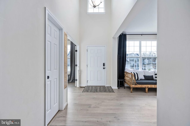 entryway featuring a towering ceiling, light wood-style floors, baseboards, and a wealth of natural light