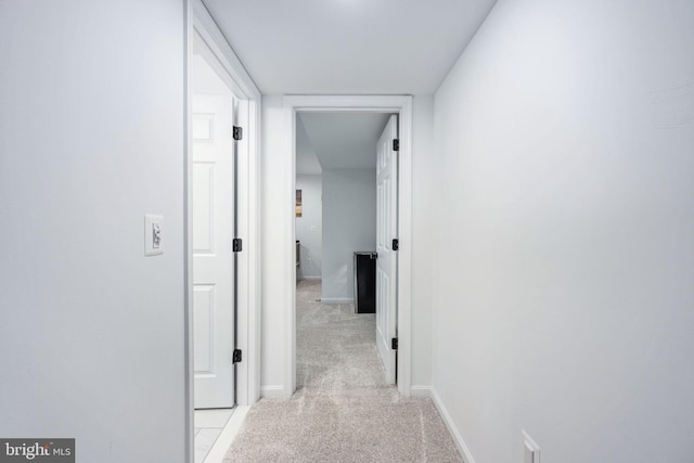 corridor featuring baseboards and light colored carpet