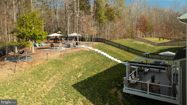 view of yard featuring a gazebo, a view of trees, a playground, and fence