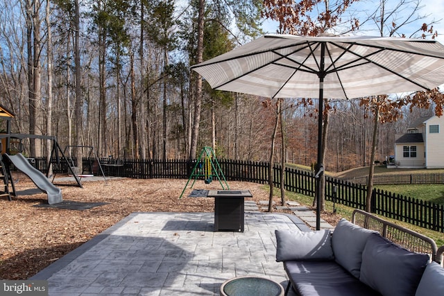 view of patio featuring an outdoor hangout area, a forest view, a playground, and a fenced backyard