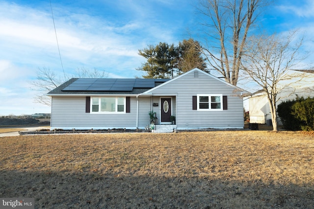 single story home featuring a front yard and roof mounted solar panels