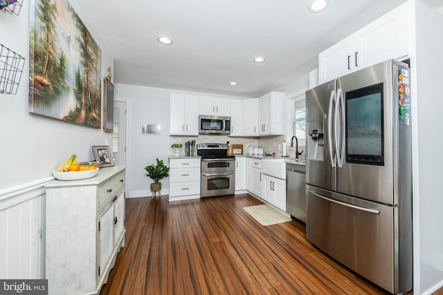 kitchen featuring white cabinets, dark wood-type flooring, stainless steel appliances, backsplash, and recessed lighting