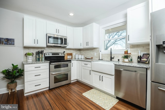 kitchen with appliances with stainless steel finishes, dark wood finished floors, white cabinetry, and a sink