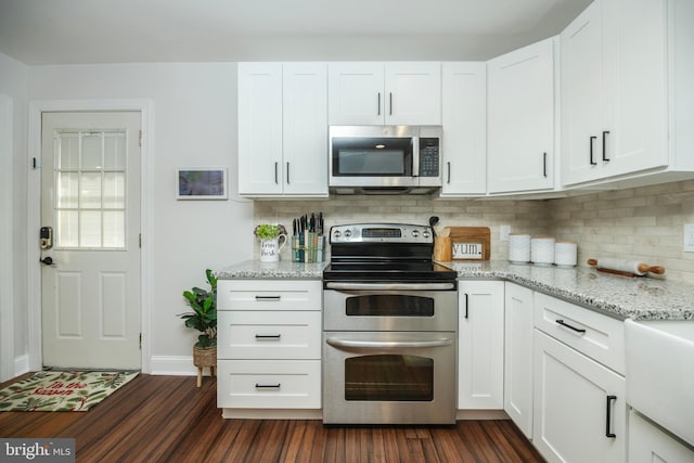 kitchen with appliances with stainless steel finishes, dark wood finished floors, white cabinetry, and tasteful backsplash