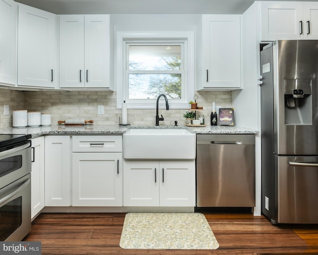 kitchen featuring stainless steel appliances, white cabinets, a sink, and light stone counters