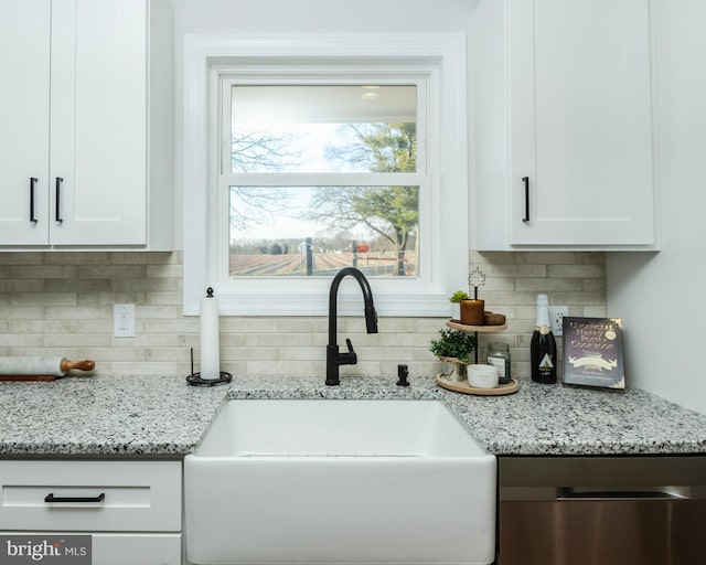 kitchen with a sink, white cabinetry, backsplash, light stone countertops, and dishwasher