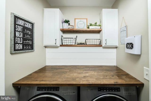 clothes washing area featuring washer and clothes dryer and cabinet space