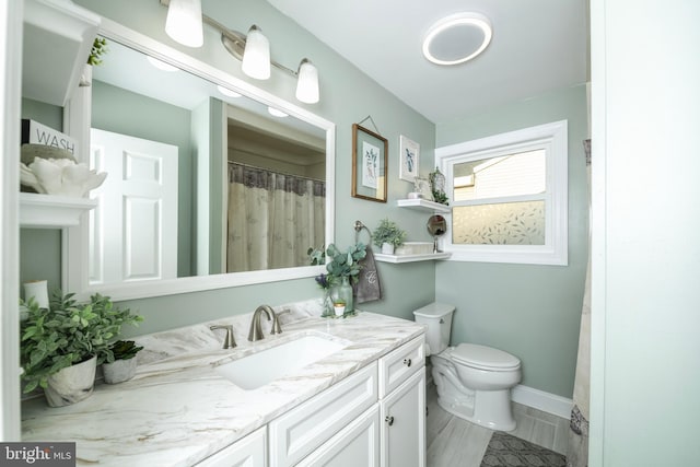 bathroom featuring toilet, baseboards, and vanity