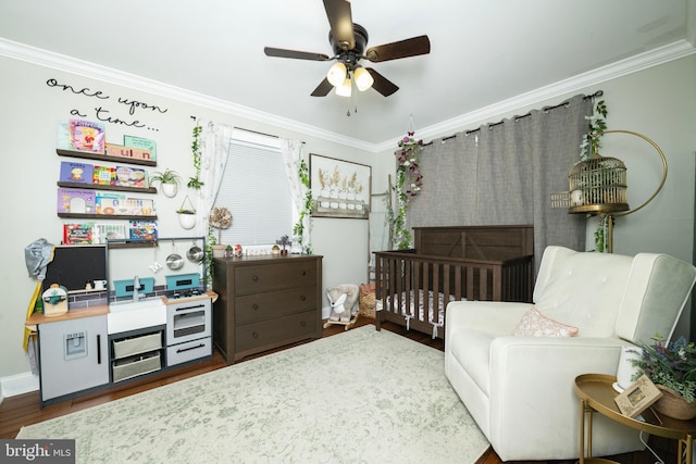 bedroom featuring ceiling fan, a nursery area, crown molding, and wood finished floors