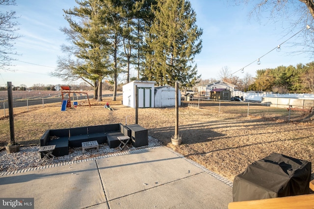 view of yard featuring an outbuilding, playground community, fence, and a shed