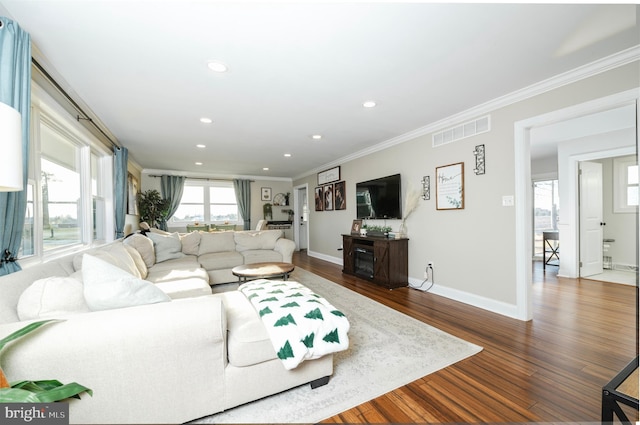 living area with baseboards, visible vents, dark wood-type flooring, crown molding, and recessed lighting