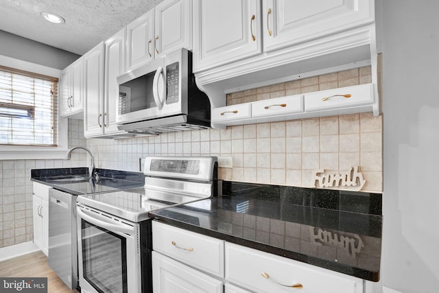 kitchen with white cabinets, appliances with stainless steel finishes, a textured ceiling, light wood-style floors, and a sink