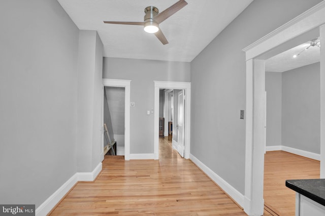 hall featuring light wood-style flooring, baseboards, and a textured ceiling