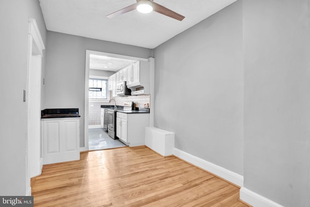 kitchen with tasteful backsplash, appliances with stainless steel finishes, light wood-style flooring, and white cabinets