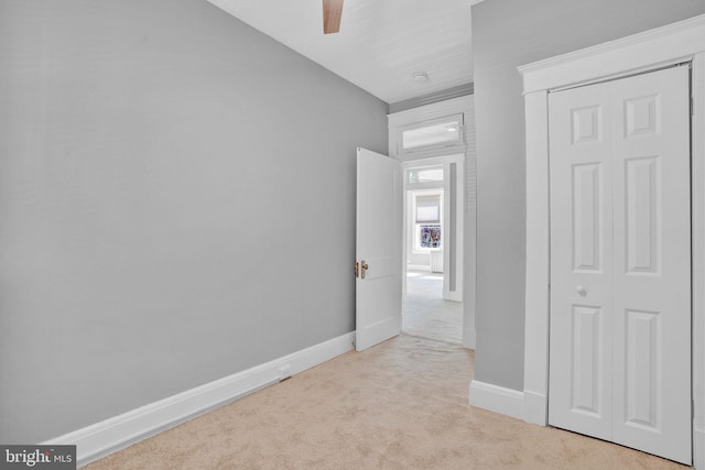 unfurnished bedroom with light carpet, ceiling fan, and baseboards