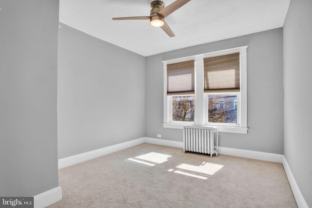 carpeted spare room with radiator, ceiling fan, and baseboards