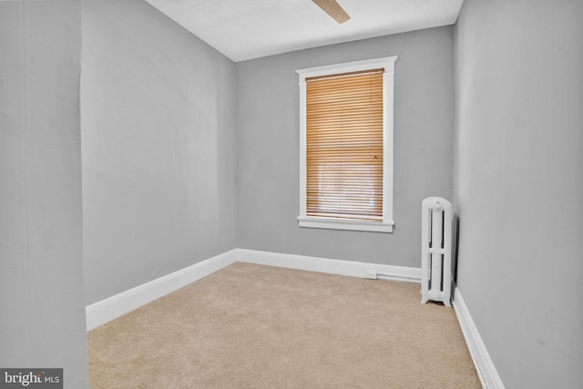 unfurnished room with radiator, carpet, and baseboards