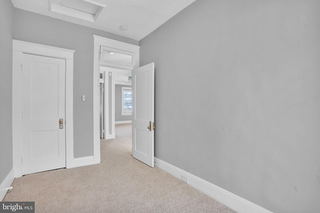 unfurnished bedroom featuring attic access, baseboards, and carpet flooring