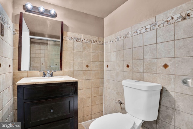 bathroom featuring toilet, tile walls, and vanity