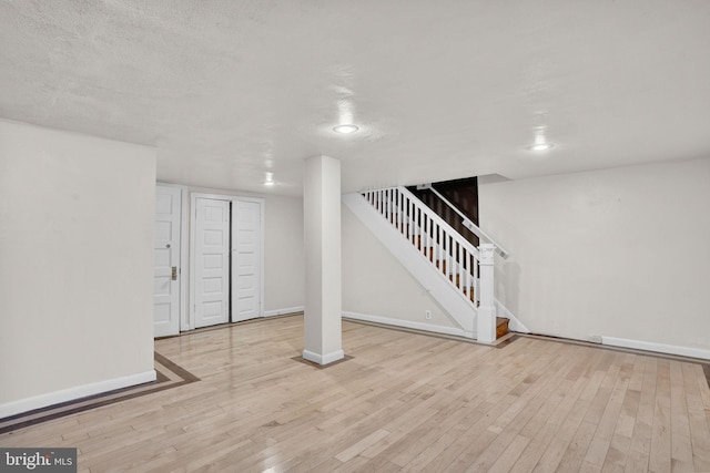 finished basement featuring stairs, recessed lighting, baseboards, and wood finished floors