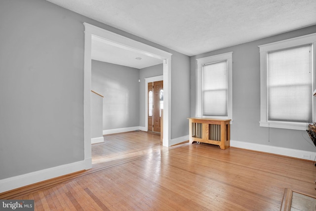 spare room featuring a textured ceiling, hardwood / wood-style floors, and baseboards