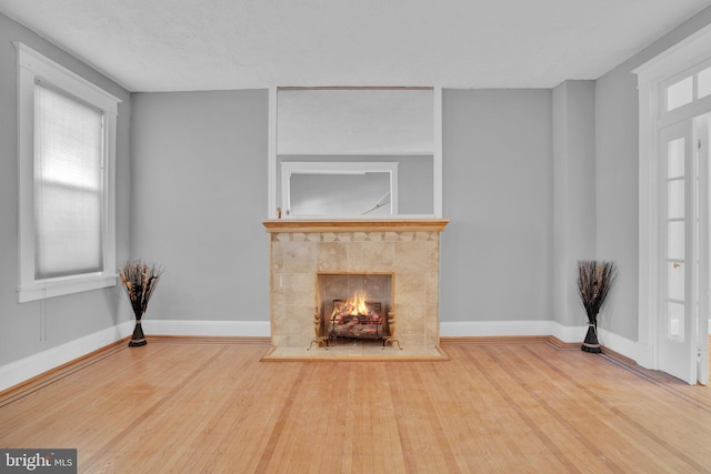 living room with baseboards, a tiled fireplace, and wood finished floors