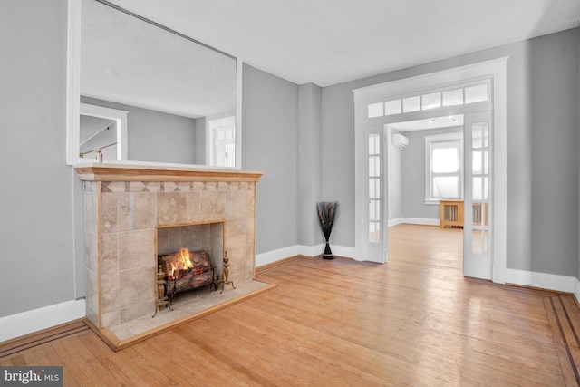 entrance foyer with a fireplace, baseboards, an AC wall unit, french doors, and wood-type flooring