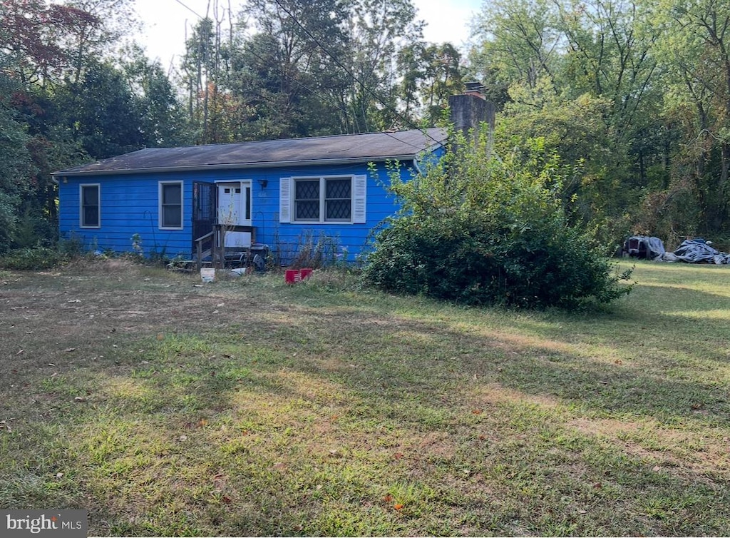 view of front of house featuring a chimney and a front lawn