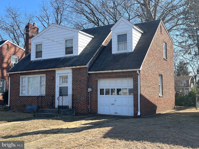 new england style home featuring an attached garage, driveway, a front lawn, and brick siding