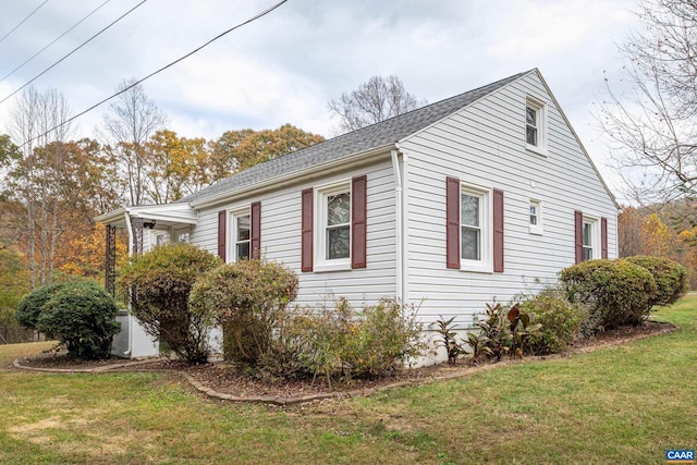 view of side of property featuring a yard and a shingled roof