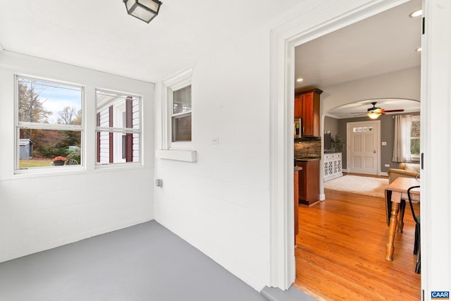 unfurnished sunroom with a ceiling fan and arched walkways