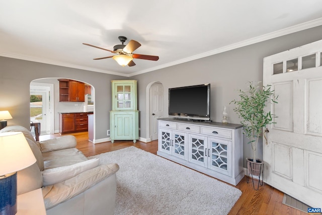 living room featuring arched walkways, wood finished floors, and crown molding