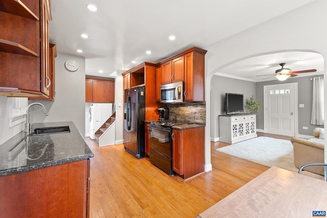 kitchen featuring arched walkways, open floor plan, black appliances, open shelves, and a sink