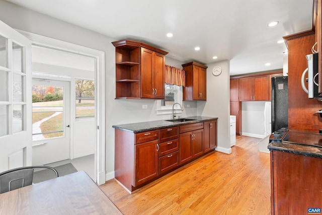 kitchen with stainless steel microwave, black refrigerator, light wood-style floors, a sink, and recessed lighting