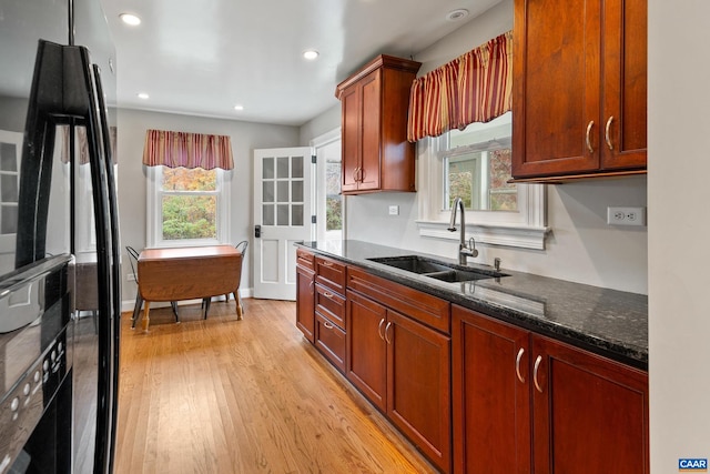 kitchen featuring light wood-style floors, dark stone countertops, a sink, and recessed lighting