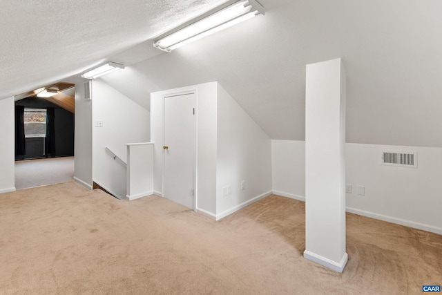 bonus room with a textured ceiling, vaulted ceiling, carpet, and visible vents