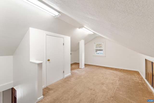 additional living space with lofted ceiling, carpet, baseboards, and a textured ceiling