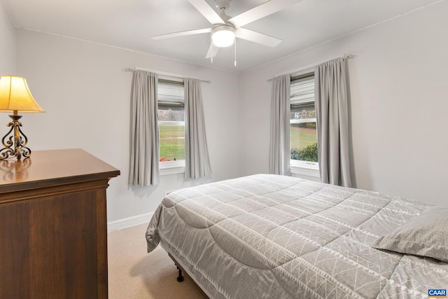 carpeted bedroom with ceiling fan, multiple windows, and baseboards